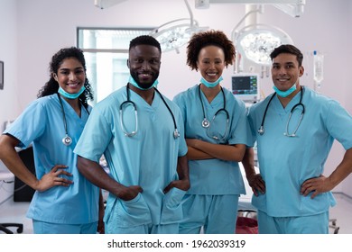 Portrait Of Smiling Diverse Surgeons Wearing Scrubs In Operating Theatre. Medicine, Health And Healthcare Services During Covid 19 Coronavirus Pandemic.