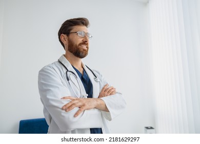 Portrait Of Smiling Doctor In Glasses Standing In Medicine Clinic Hall And Looking Away