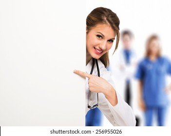 Portrait Of A Smiling Doctor Pointing Her Finger To A Blank Board