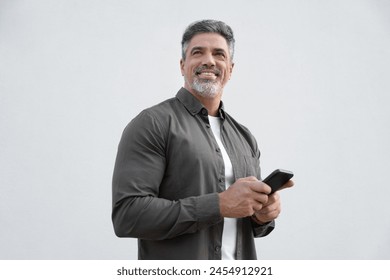 Portrait of smiling dreaming hispanic business man using smartphone mobile phone device for online financial bank transactions. 40s freelancer entrepreneur holding cellphone isolated, white background - Powered by Shutterstock