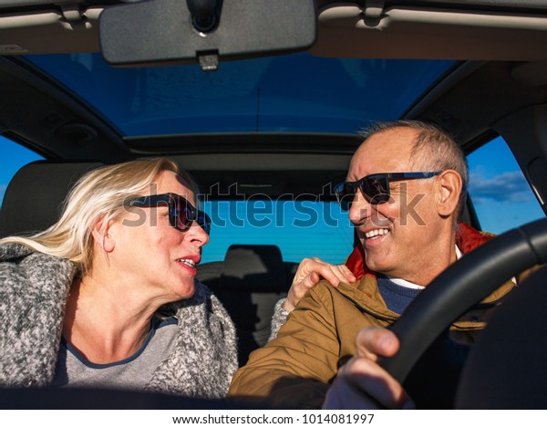 Portrait of\
smiling elderly couple driving\
car.