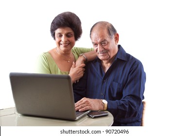 Portrait Of A Smiling Elderly East Indian Couple On Computer Laptop