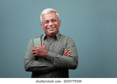 Portrait of a smiling elderly man of Indian ethnicity  holding a mobile phone