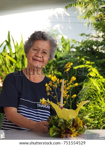Portrait of a smiling elderly woman standing and holding krathong. Loy Krathong festival in Thailand.