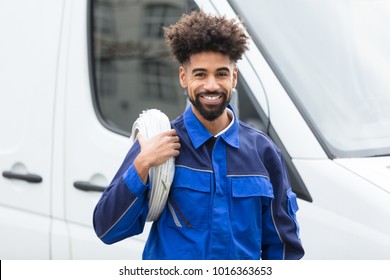 Portrait Of Smiling Electrician With White Cable Coil Standing By Van