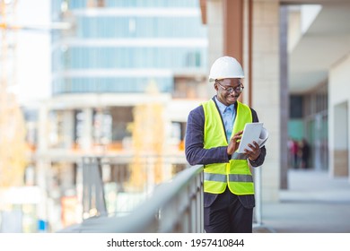 Portrait of smiling Engineer - Architect looking at camera. Working on a new office building. Happy mid adult engineer. Man engineer walking on construction site, holding tablet.