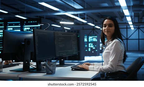 Portrait of smiling engineer overseeing data center, making improvements and updates to ensure system can handle networking tasks. Upbeat server room worker tracking network traffic, camera B