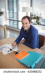 Portrait of smiling executive using digital tablet at desk in office