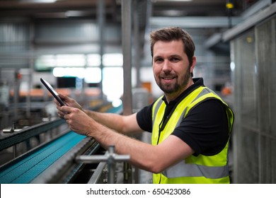 Portrait Of Smiling Factory Worker Using A Digital Tablet In Factory