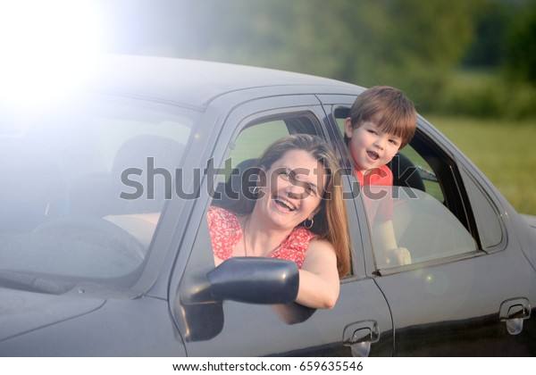 Portrait of a\
smiling family in the car at sunset. Happy mother and son in a\
family car.  Holiday and travel\
concept