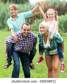 Portrait of smiling family with children enjoying vacation in park - Shutterstock ID 330558911