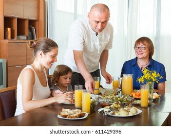 Portrait Of Smiling Family  Eating Fish With Juice At Home