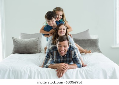 Portrait Of Smiling Family Playing On Bed In Bedroom At Home