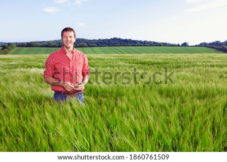 A portrait of a smiling farmer standing in a barley field