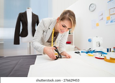 Portrait Of Smiling Fashion Designer Cutting Fabric In Studio - Powered by Shutterstock