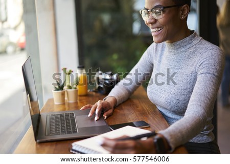 Portrait of smiling female CEO communicating with employees through online video chat controlling  their work being in business trip doing remote job in coffee shop using free wireless internet