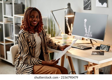 Portrait Of Smiling Female Creator Holding Photographs And Looking At Camera While Choosing One For Publishing, Copy Space