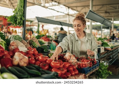 Portrait of smiling female customer standing at farmer's market and choosing fresh organic tomato from market stall. Happy woman selecting fresh healthy food at greengrocery market. Copy space. - Powered by Shutterstock