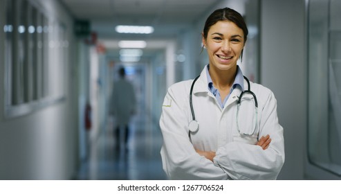 Portrait Of Smiling Female Doctor Satisfied With His Job In A Corridor Of A Hospital. Concept Of Medicine, Technology, Health Care And People, Hospital