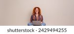 Portrait of smiling female entrepreneur working online over laptop while sitting on white background