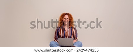 Portrait of smiling female entrepreneur working online over laptop while sitting on white background