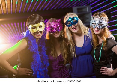 Portrait Of Smiling Female Friends Wearing Masquerade In Bar