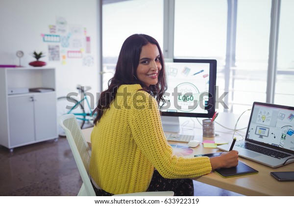 Portrait of smiling female graphic designer\
working in creative\
office