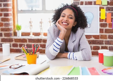 Portrait Of Smiling Female Interior Designer Sitting At Office Desk