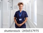 Portrait Of Smiling Female Nurse Wearing Uniform In Hospital Corridor With Security Lanyard