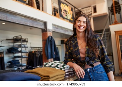 Portrait Of Smiling Female Owner Of Fashion Store Standing In Front Of Clothing Display