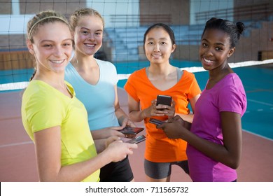 Portrait of smiling female players using mobile phones in volleyball court - Powered by Shutterstock