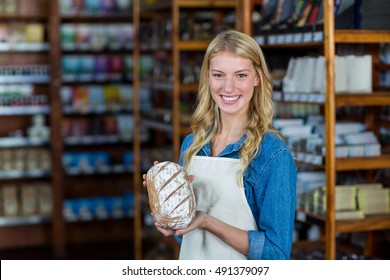 Portrait of smiling female staff holding bread in super market - Powered by Shutterstock