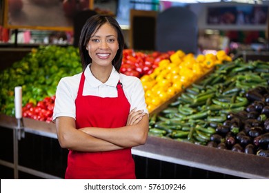 Portrait of smiling female staff standing with arms crossed in organic section of super market - Powered by Shutterstock