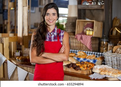 Portrait of smiling female staff standing with arms crossed at bakery shop in supermarket - Powered by Shutterstock