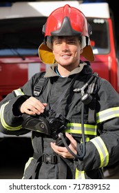 Portrait Of Smiling Fireman Wearing Fire Fighter Turnouts And Red Helmet