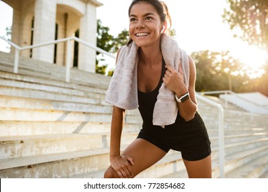 Portrait of a smiling fitness girl with towel resting after work out outdoors
