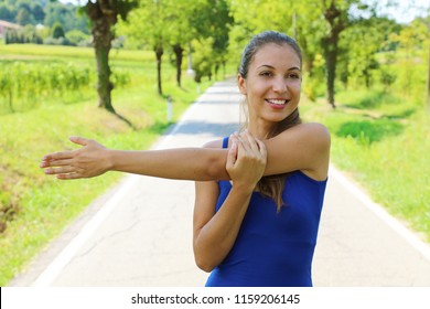 Portrait of a smiling fitness woman stretching arms outdoor