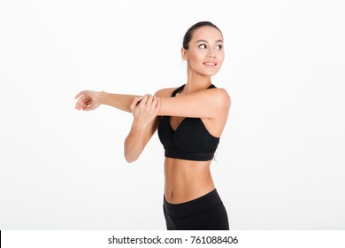 Portrait of a smiling fitness woman stretching her hands isolated over white background