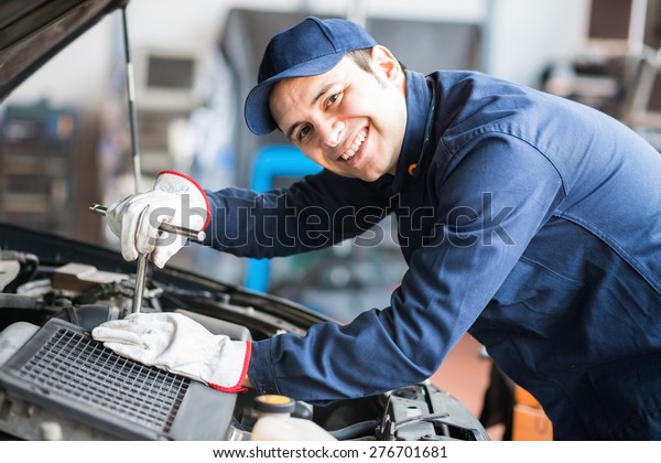 Portrait\
of a smiling fixing a car engine in his\
garage