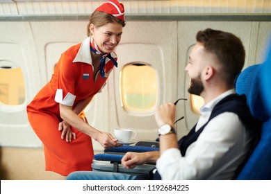 Портрет улыбающейся стюардесса, обслуживающий кофе молодому бизнесмену в первом классе, копия пространства