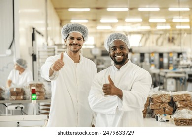 Portrait of smiling food factory quality control inspectors in sterile uniform giving thumbs up and approval - Powered by Shutterstock