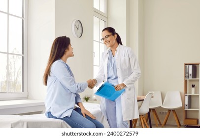 Portrait of smiling friendly female doctor therapist shaking hands with a young patient woman sitting on the couch after medical examination in clinic. Medicine and health care concept. - Powered by Shutterstock