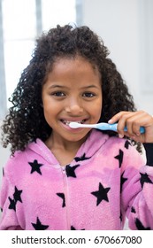 Portrait of smiling girl brushing her teeth in bathroom at home - Shutterstock ID 670667080