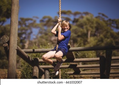 Portrait of smiling girl climbing rope during obstacle course in boot camp - Powered by Shutterstock