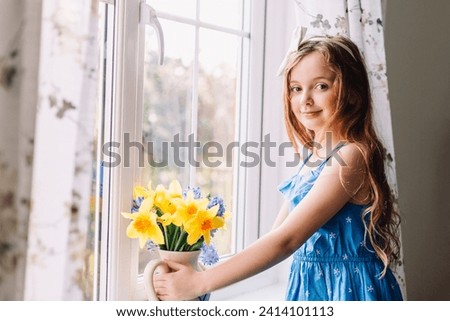 Portrait of smiling girl with flower vase of daffodils and hyacinths at home