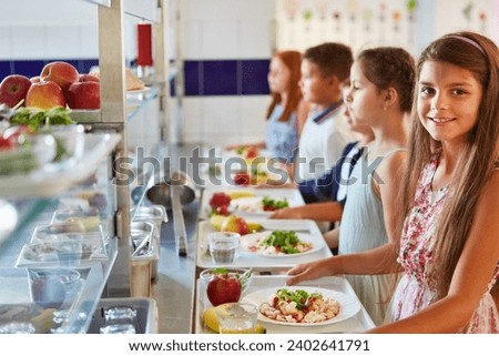 Portrait of smiling girl with food tray standing in line by friends during lunch break in school cafeteria