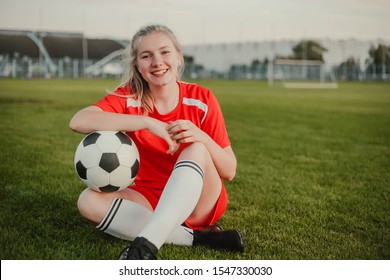 Portrait of smiling girl football player with soccer ball sitting on the grass, copy space - Powered by Shutterstock