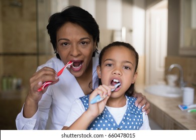 Portrait of smiling girl and grandmother brushing teeth in bathroom