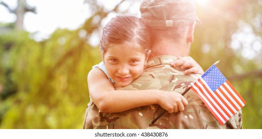 Portrait Of Smiling Girl Holding American Flag While Hugging Army Officer Father In Park