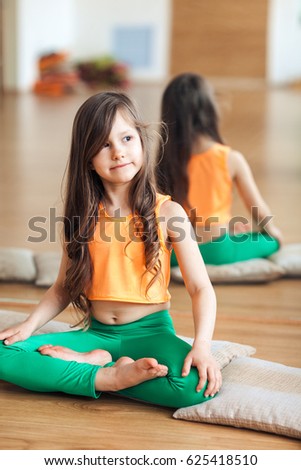 Portrait of smiling girl practicing yoga, sitting in Padmasana exercise, Lotus pose, working out wearing sportswear
